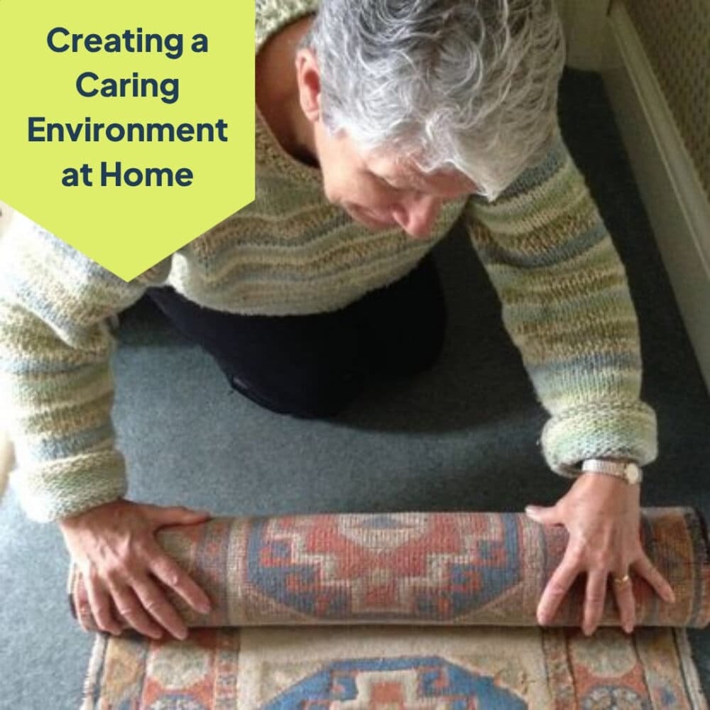 Older adult kneeling and rolling up a patterned rug; text: "Creating a Caring Environment at Home. - Home Instead