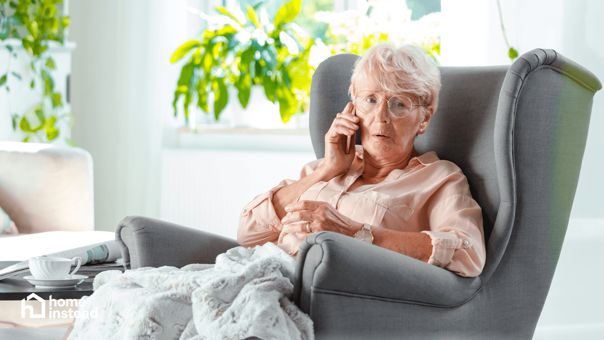 Concerned older woman on phone in armchair potentially receiving scam call at home