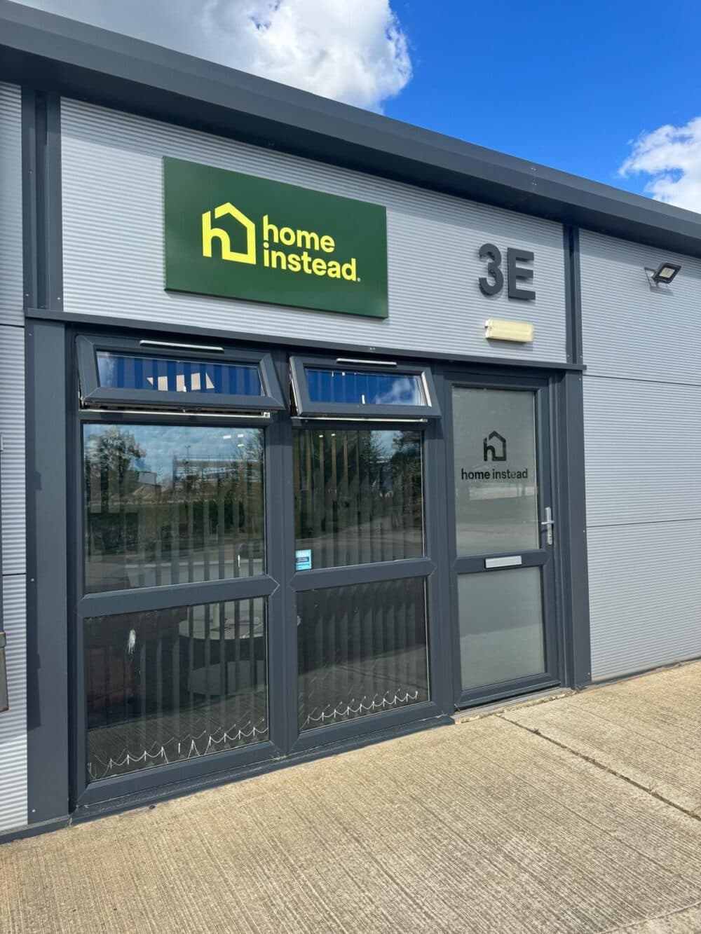 A Home Instead office with a green sign above the entrance reading "home instead" and labeled unit 3E. - Home Instead