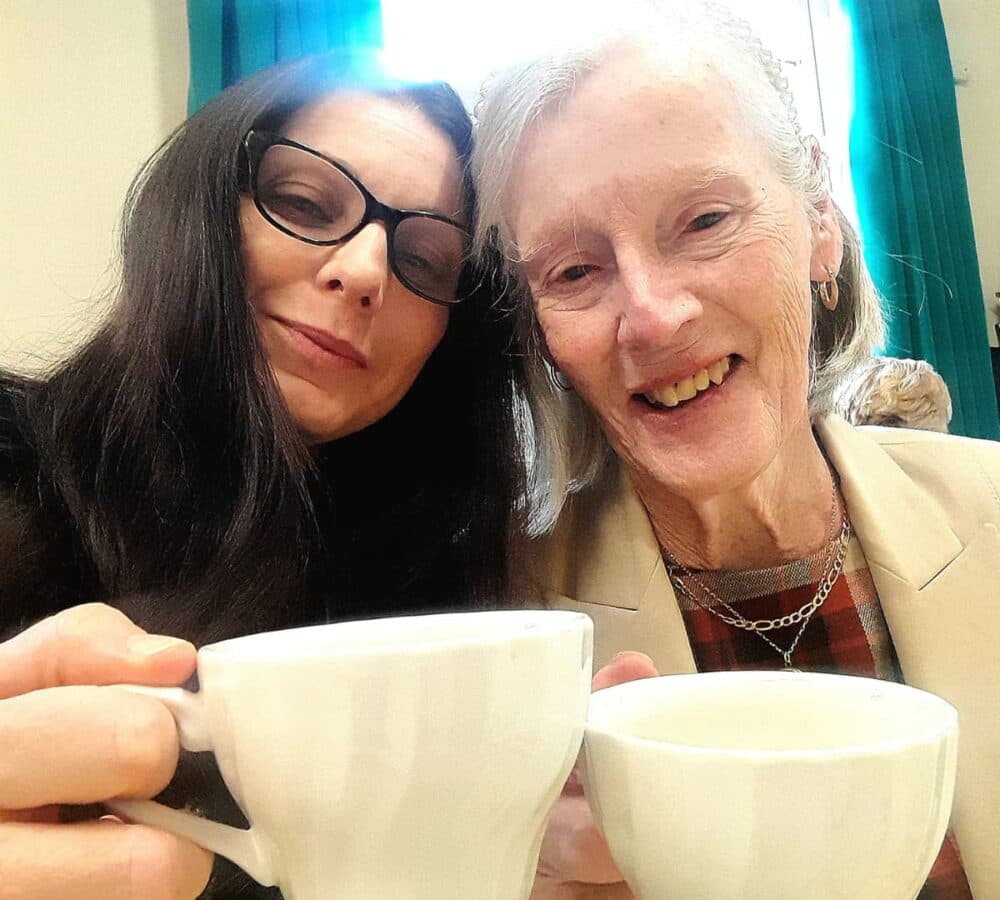 Two women having coffee together both happy and smiling