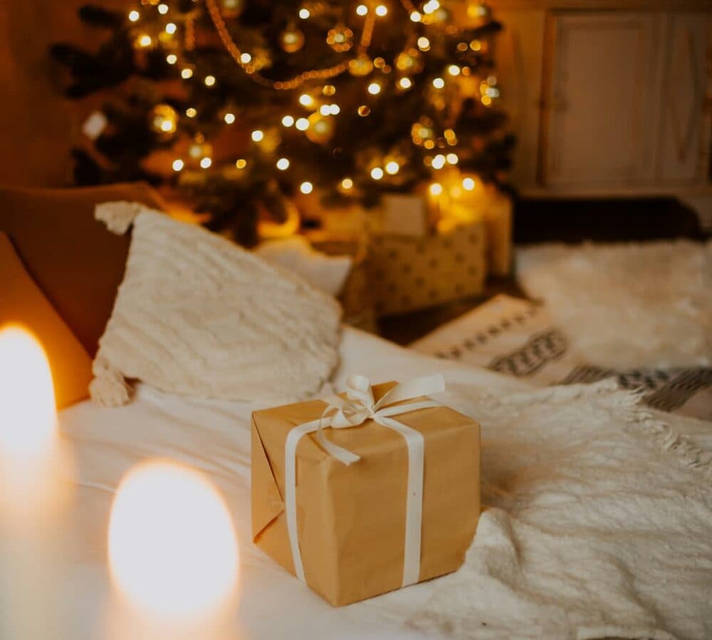 A brown gift under the Christmas tree with christmas lights