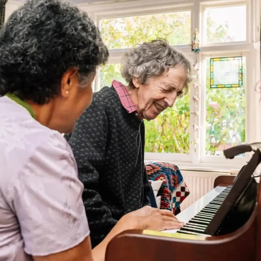 Home Instead Care Professional playing the piano with her client