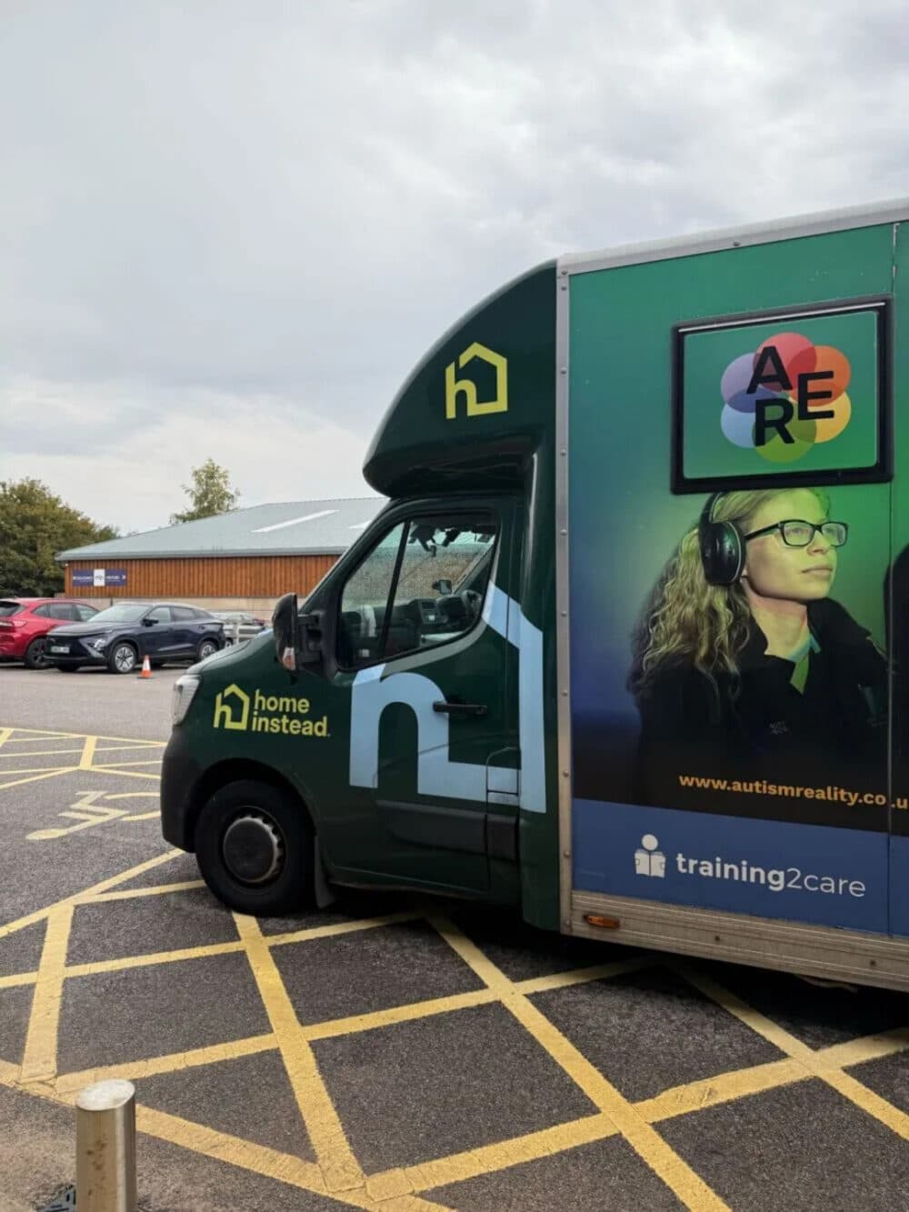 A green van with "home instead" branding parked in a yellow-striped disabled parking bay. - Home Instead