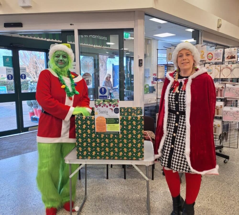 A santa and a woman with a donation box on the table