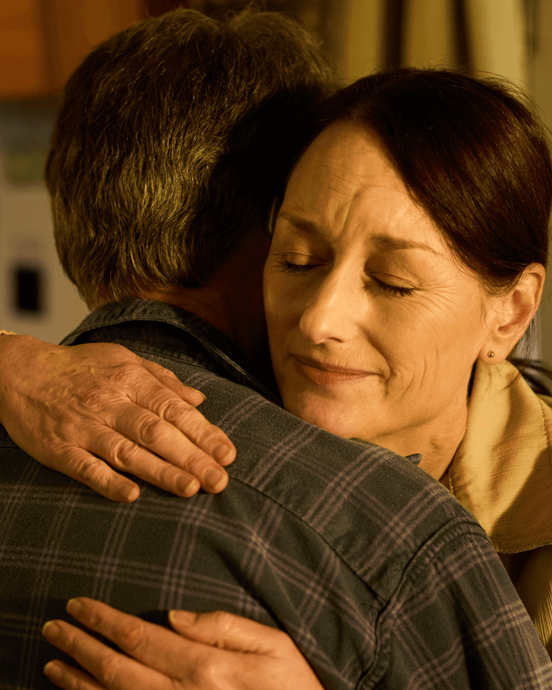 A woman with closed eyes hugs a man closely, expressing comfort and emotion. - Home Instead