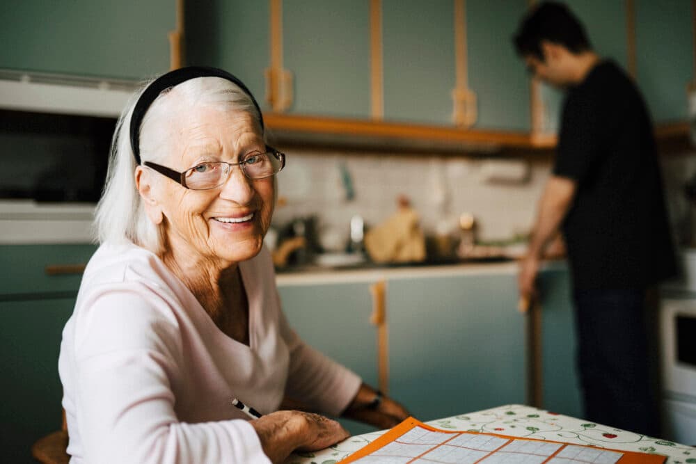 Portrait of smiling elderly woman while male care professional standing in background at home