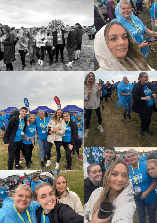A group of people in blue shirts smiling and posing together at an outdoor charity event. - Home Instead