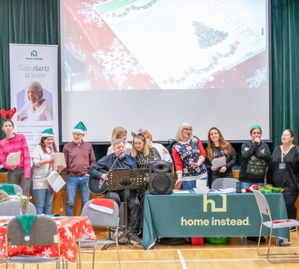 Many people singing together and wearing colourful Christmas clothes
