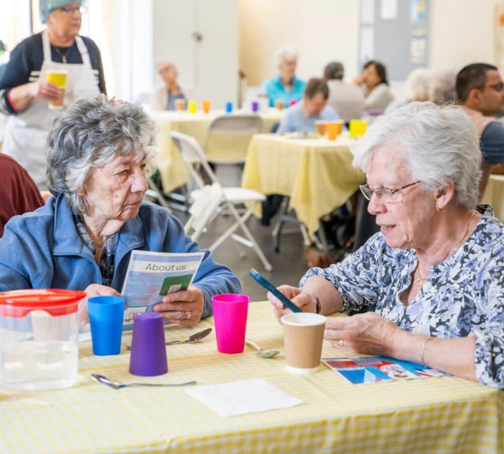 Two ladies sitting on the table while chatting