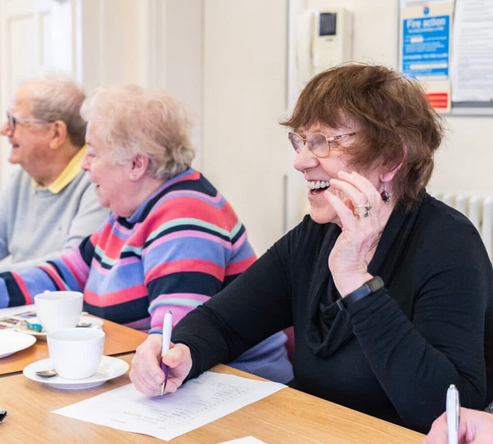 An older female adult with brown hair and wearing eyeglasses happy and smiling