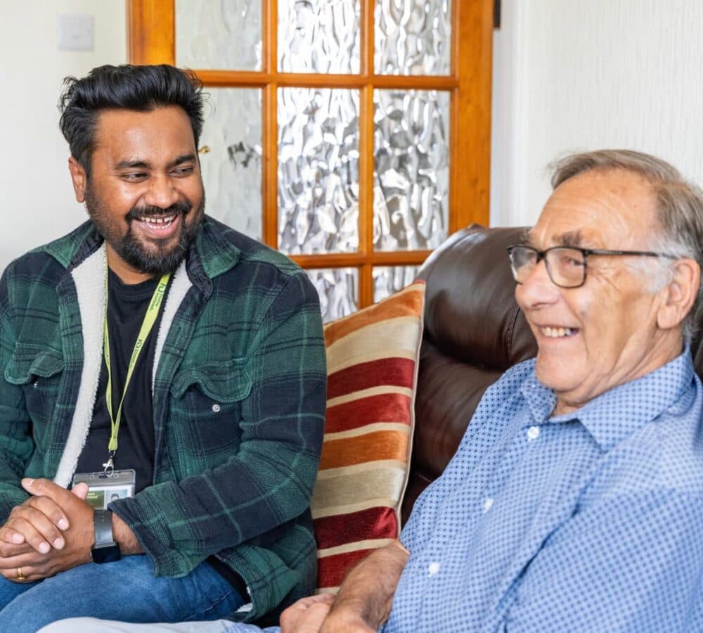 Two men chatting and happy and smiling while sitting on the couch