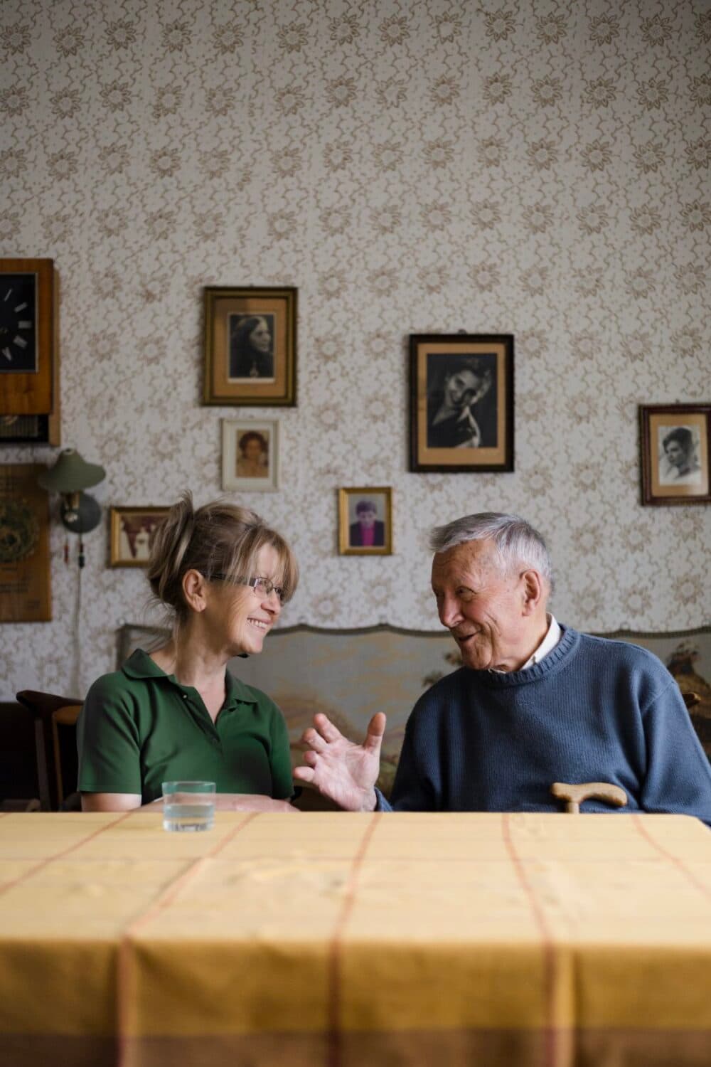 Senior man and younger woman talking in the living room