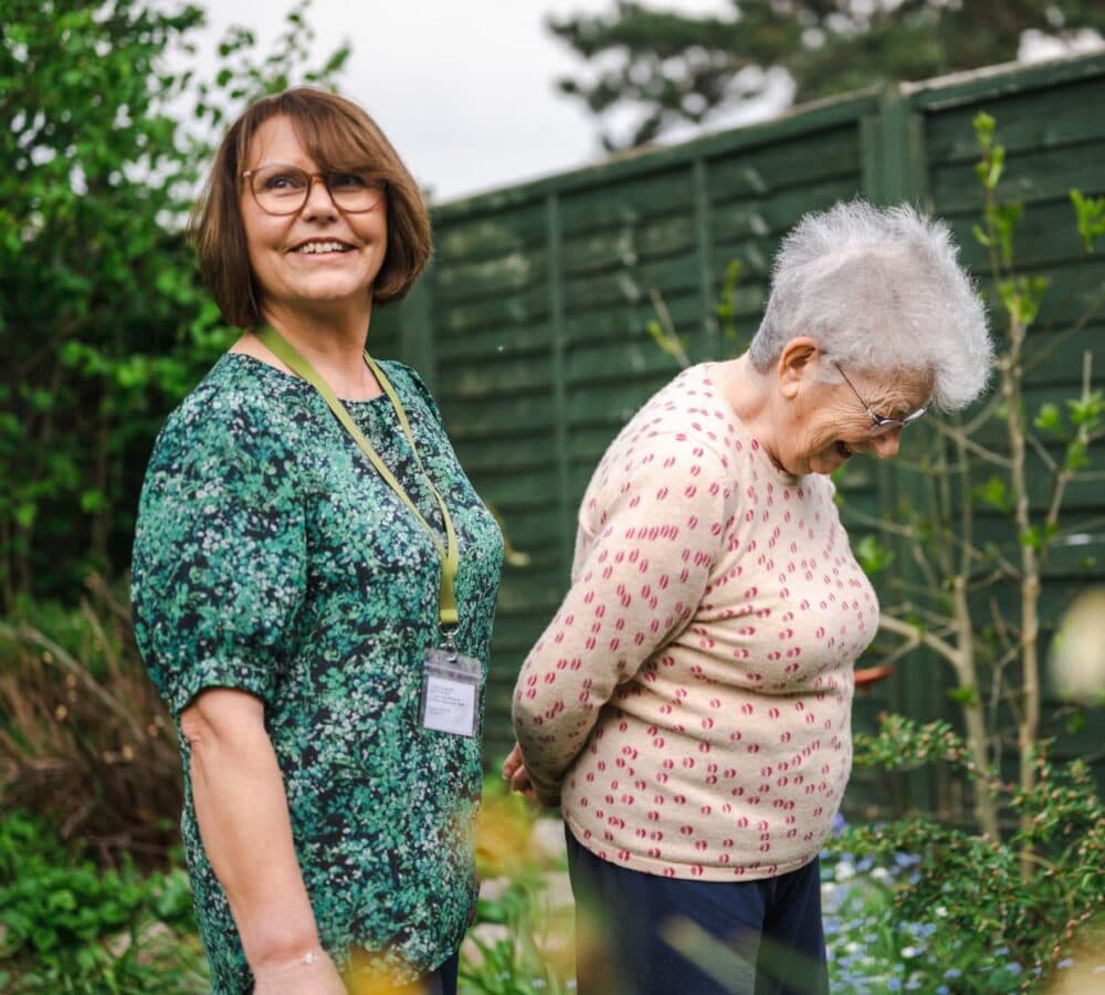 Two women having a walk in the garden both happy and smiling