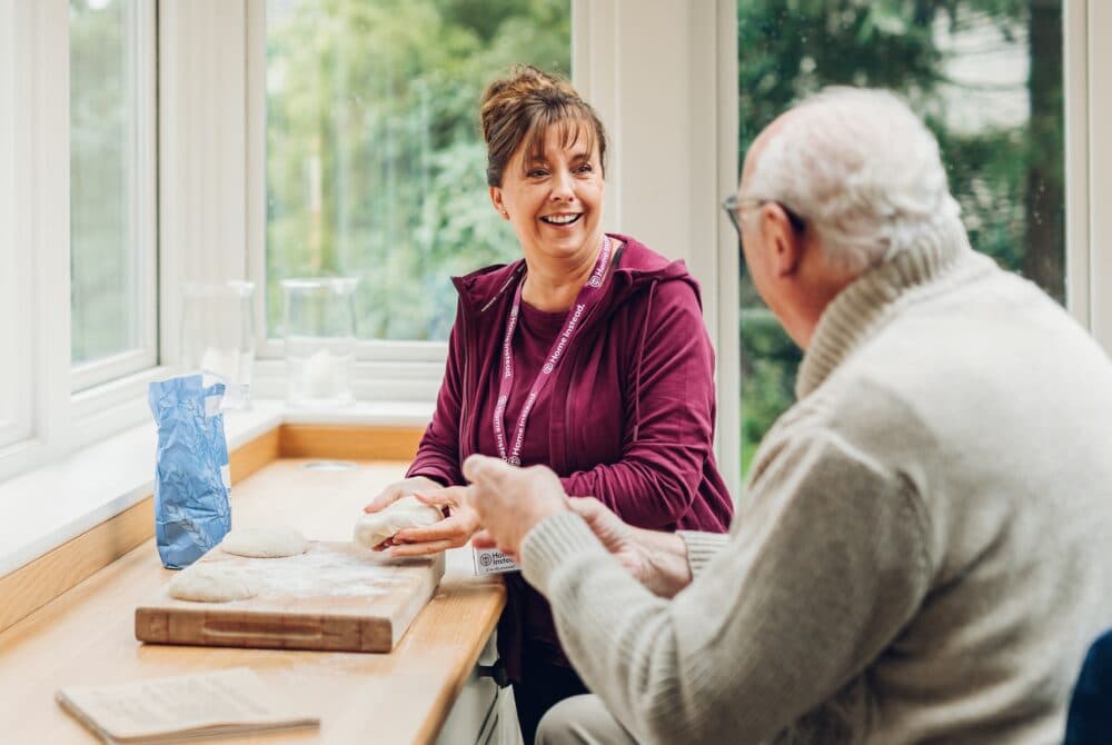 Elderly man and his Home Instead carer preparing the dough together to make bread