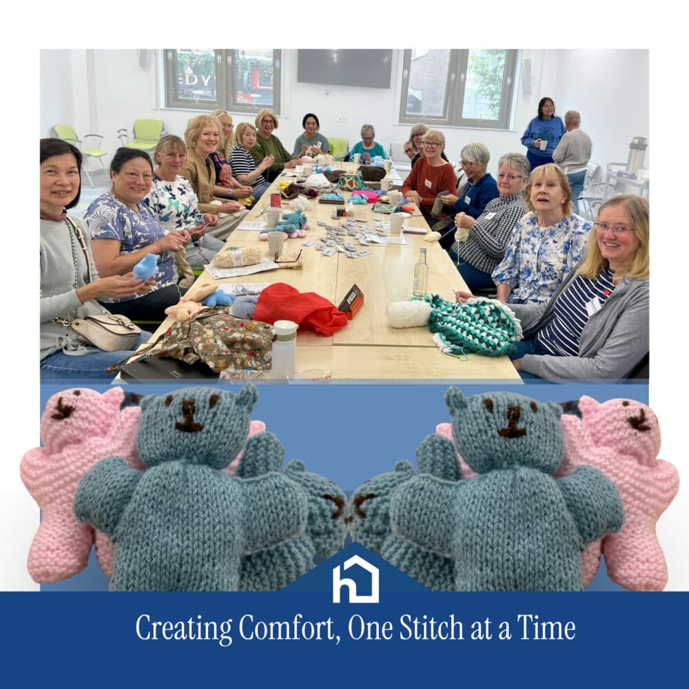 A group of women knit together at a long table; knitted teddy bears are displayed in front. - Home Instead
