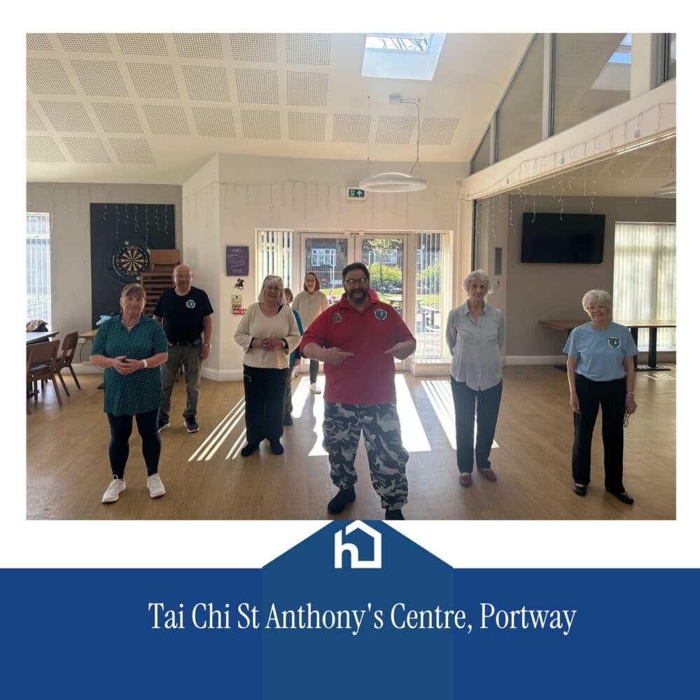 A group of people practising Tai Chi indoors at St Anthony's Centre, led by an instructor in a red shirt. - Home Instead