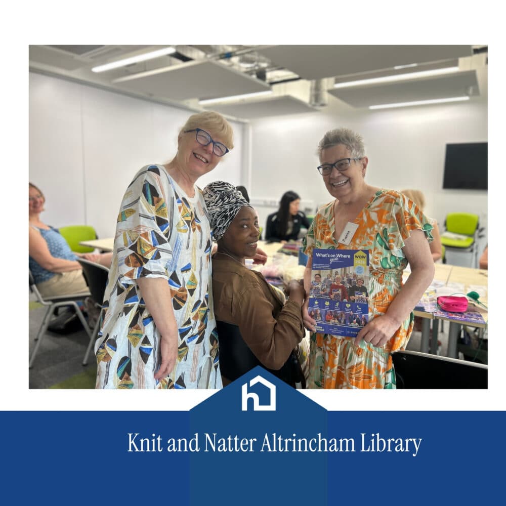 Three smiling women at a knitting group in a bright room, one holding a book. Text: Knit and Natter Altrincham Library. - Home Instead