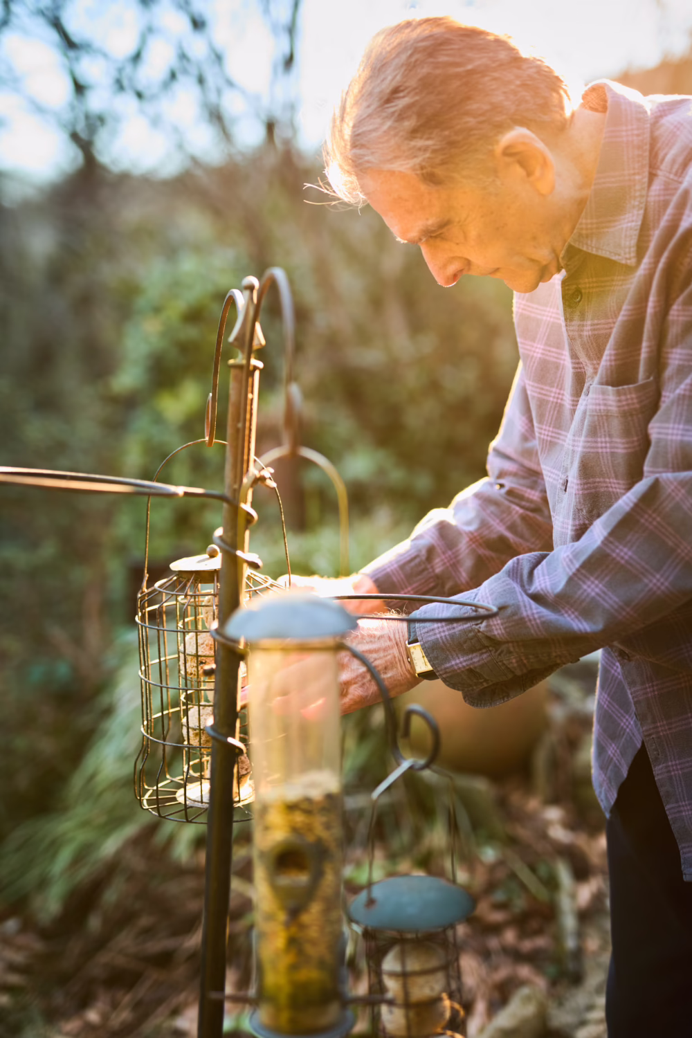 Elderly adult refilling the bird feeder