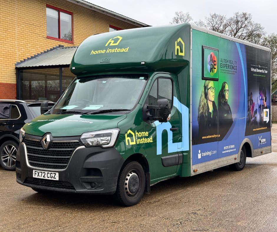 A green Home Instead van with promotional graphics parked outside a brick building. - Home Instead