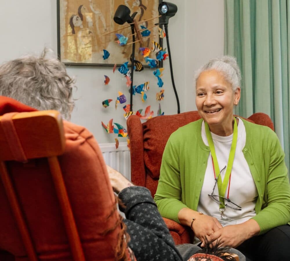 An older female adult with grey hair happy and smiling while chatting with someone inside the house