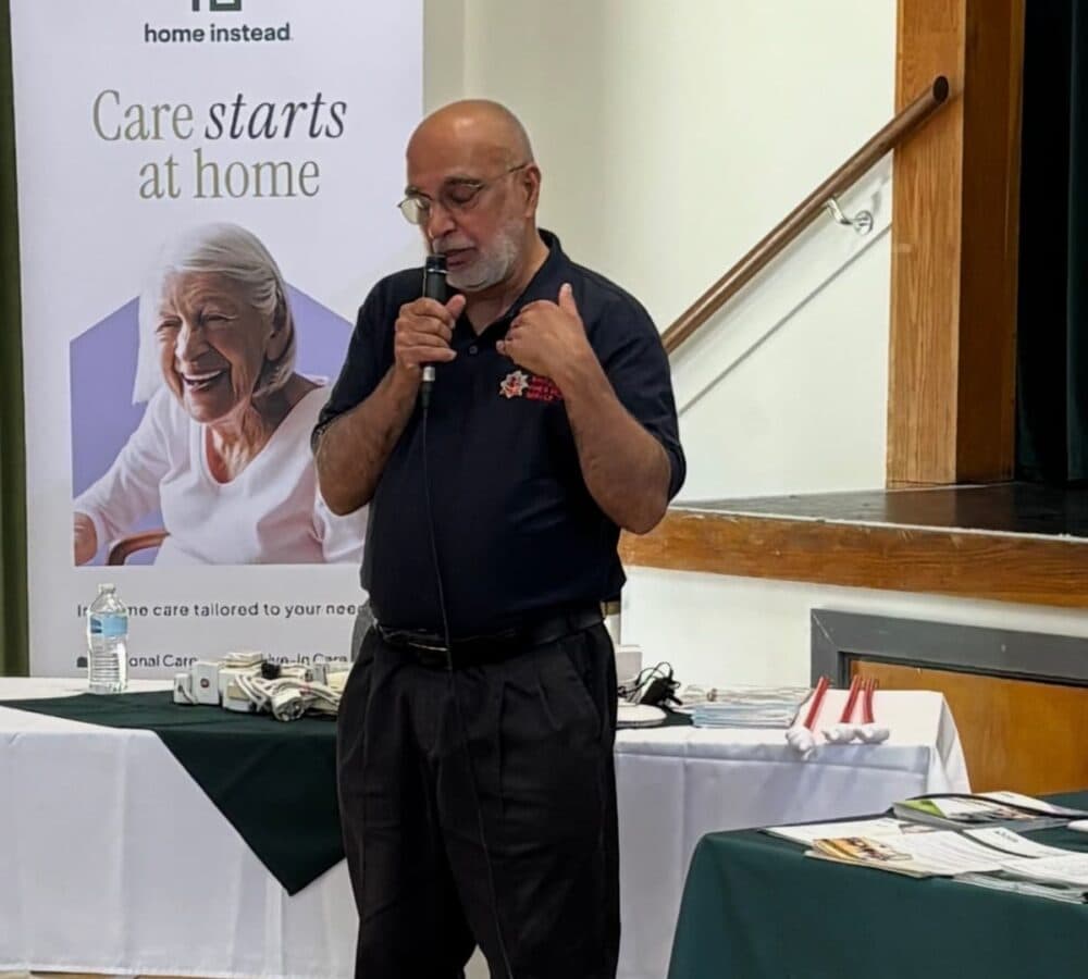 an older male adult standing in front while speaking