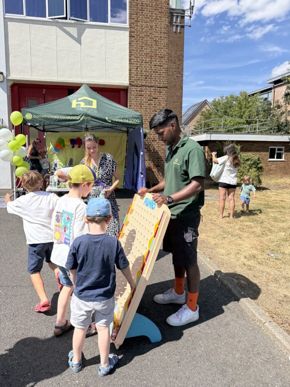 Children eagerly dropping discs into a Plinko board at Home Instead Chingford’s community Open Day.