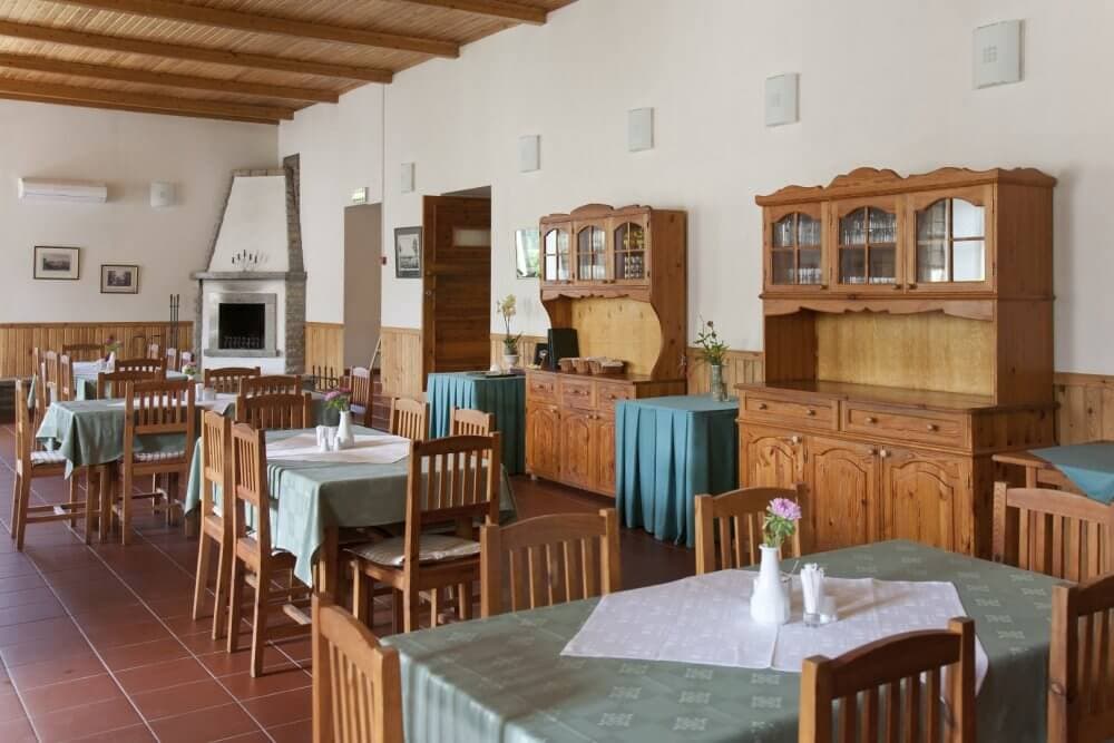 Cozy restaurant with wooden chairs and tables, green tablecloths, and cabinets, featuring a fireplace and decoration. - Home Instead