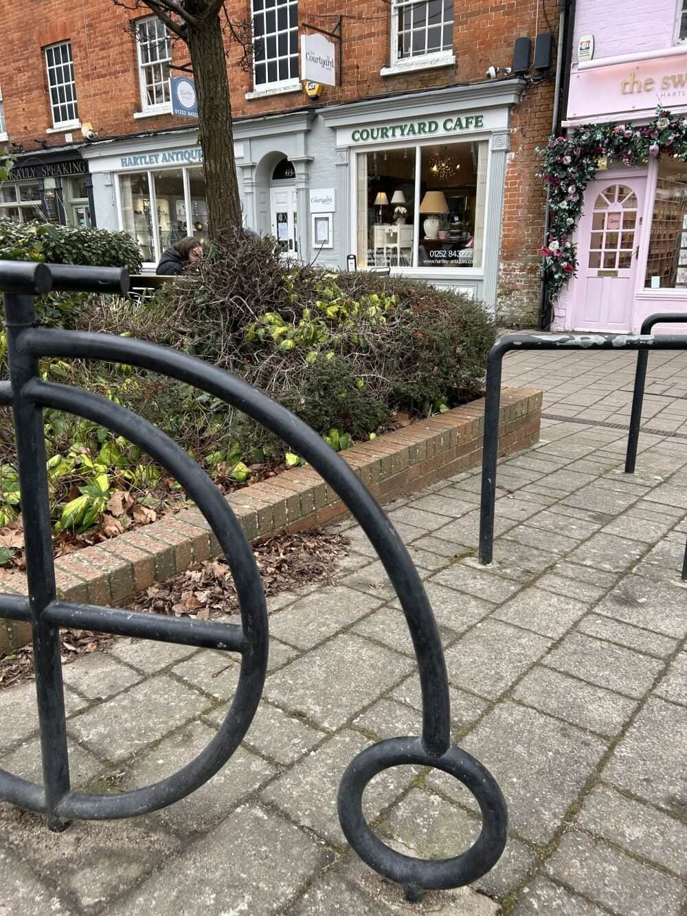 Home Instead Basingstoke picture of the Courtyard Café in Hartley Wintney with a black cycle sculpture in the foreground and a tree on the left.