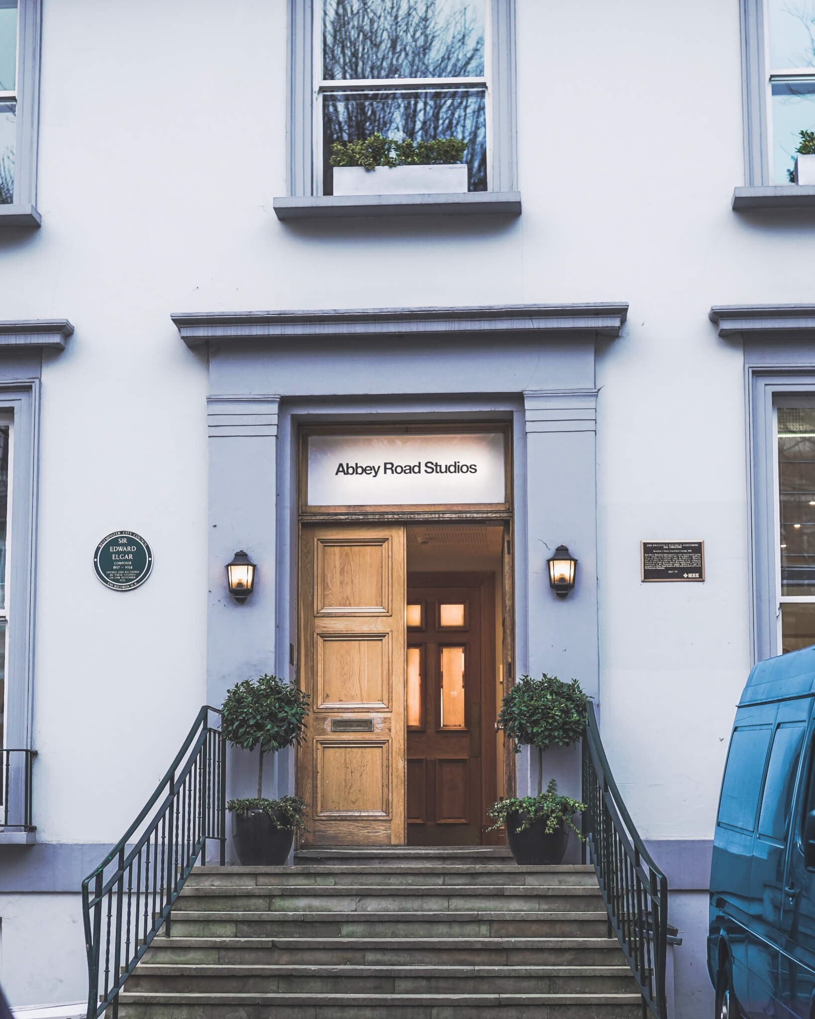 Entrance of Abbey Road Studios with open door, external staircase, and a blue van parked nearby. - Home Instead