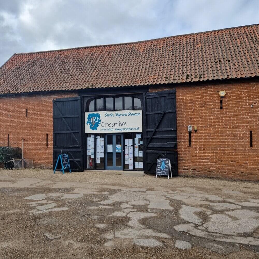A large brick building with black wooden doors houses the "Art Creative" studio, shop, and showcase. - Home Instead