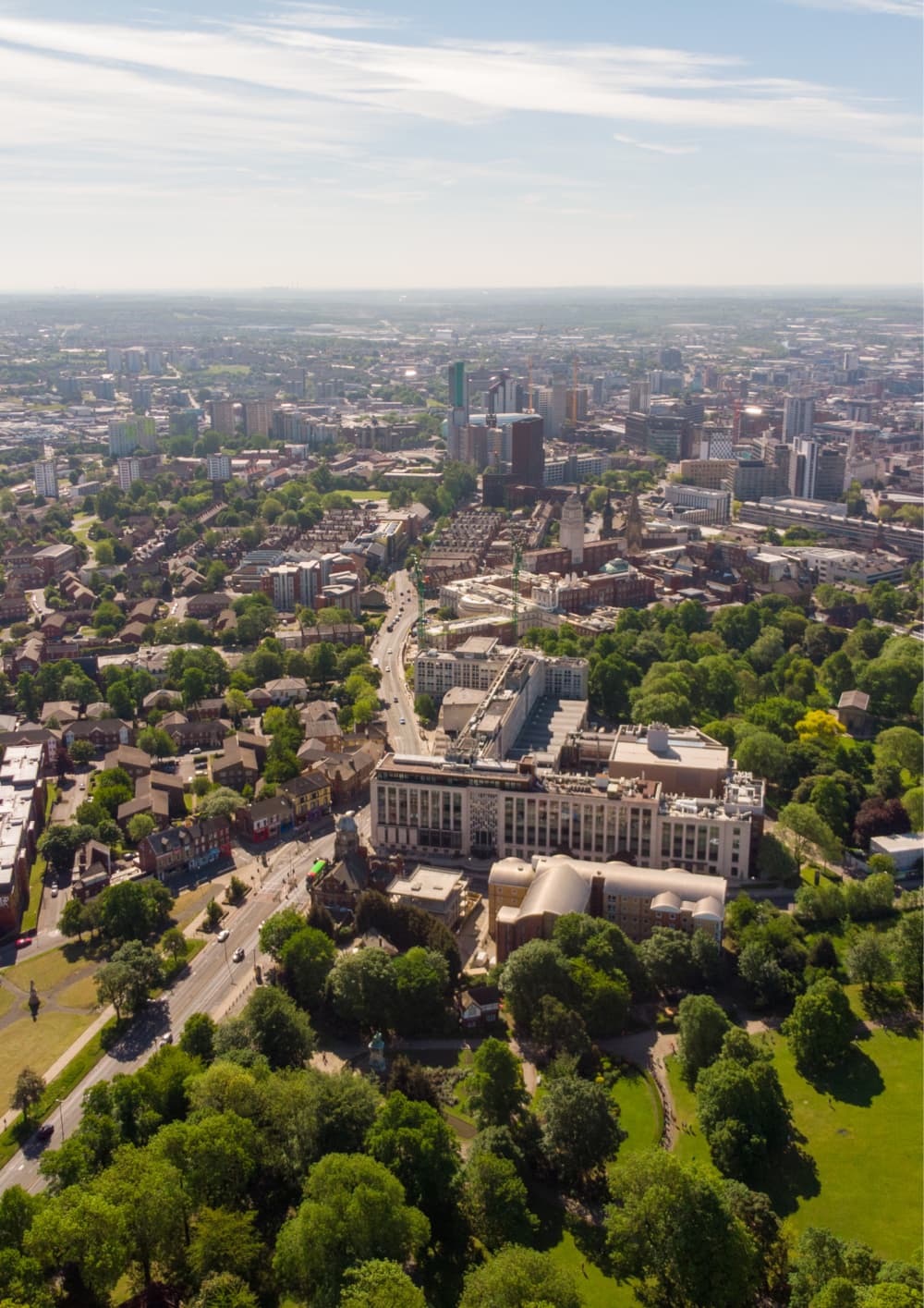 Aerial view of a cityscape with buildings, green spaces, and tree-lined roads on a clear day. - Home Instead