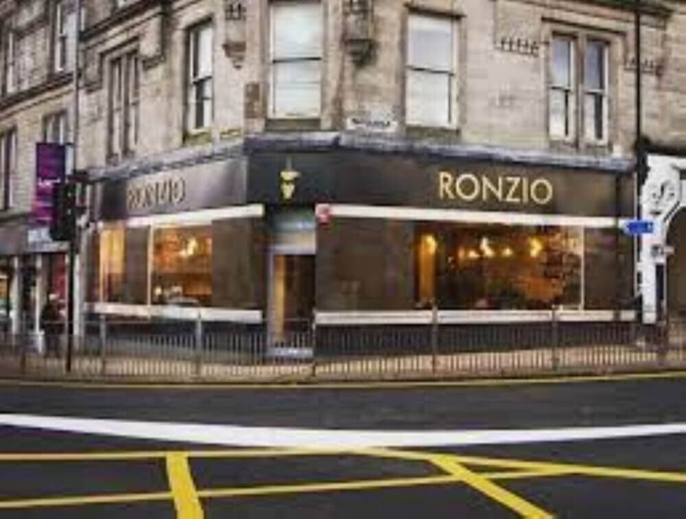 Corner view of Ronzio cafe with large windows and a dark exterior on a city street with a crossing in front. - Home Instead