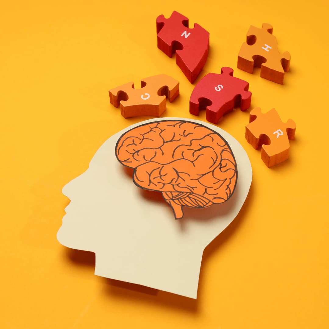 Illustration of a human head silhouette with a brain and scattered puzzle pieces on an orange background. - Home Instead