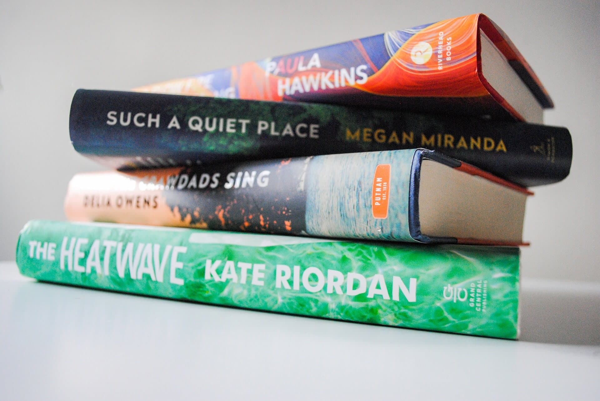 A stack of four books: "A Slow Fire Burning," "Such a Quiet Place," "Where the Crawdads Sing," and "The Heatwave. - Home Instead