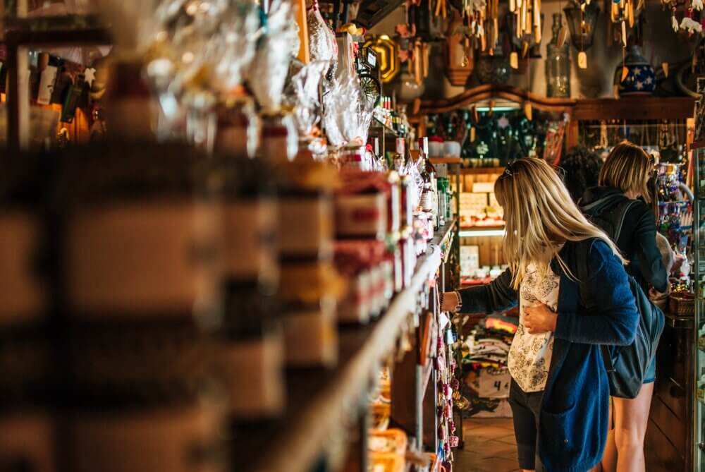 Two people browsing items in a cozy, warmly lit store with shelves stocked with various products. - Home Instead
