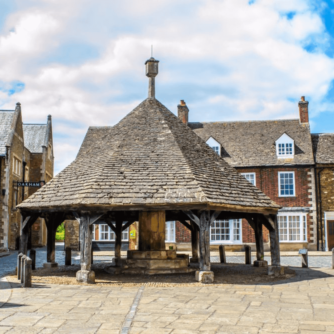 A historic stone market building with a conical roof in a town square surrounded by traditional stone buildings. - Home Instead