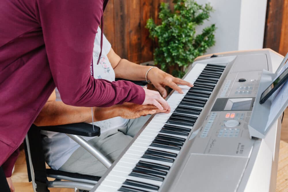 Care Professional helping client play keyboard - Home Instead