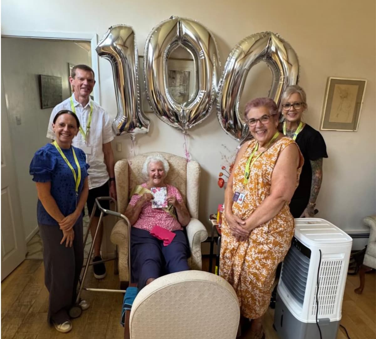 An older adult celebrating her birthday while surrounded with people inside her home