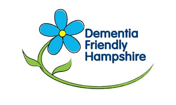 A blue flower with green stem next to the text "Dementia Friendly Hampshire" on a white background. - Home Instead