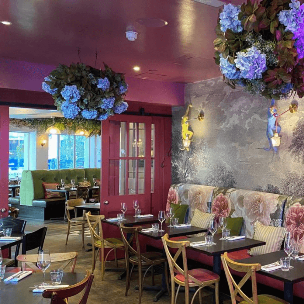 Colorful restaurant interior with floral decor, vibrant seating, elegant table settings, and floral ceiling fixtures. - Home Instead