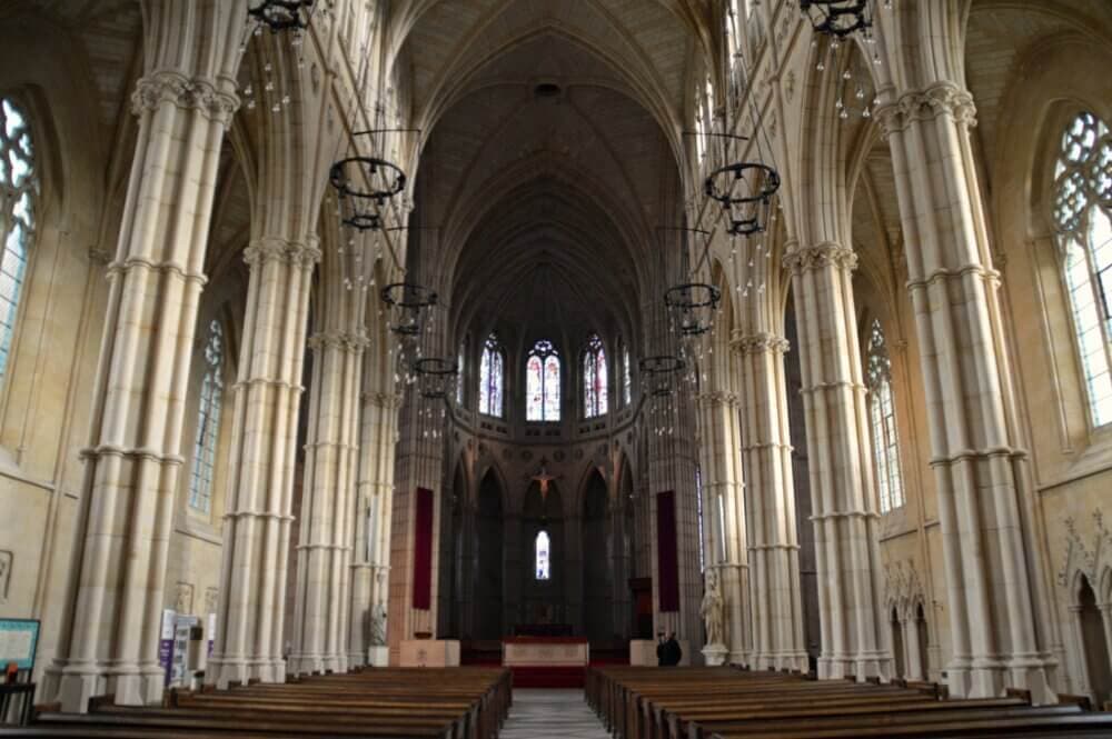 Interior of a grand cathedral with tall columns, vaulted ceilings, and a view towards the altar at the far end. - Home Instead