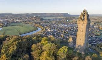 Aerial view of the Wallace Monument in Stirling, Scotland, surrounded by greenery and a winding river. - Home Instead