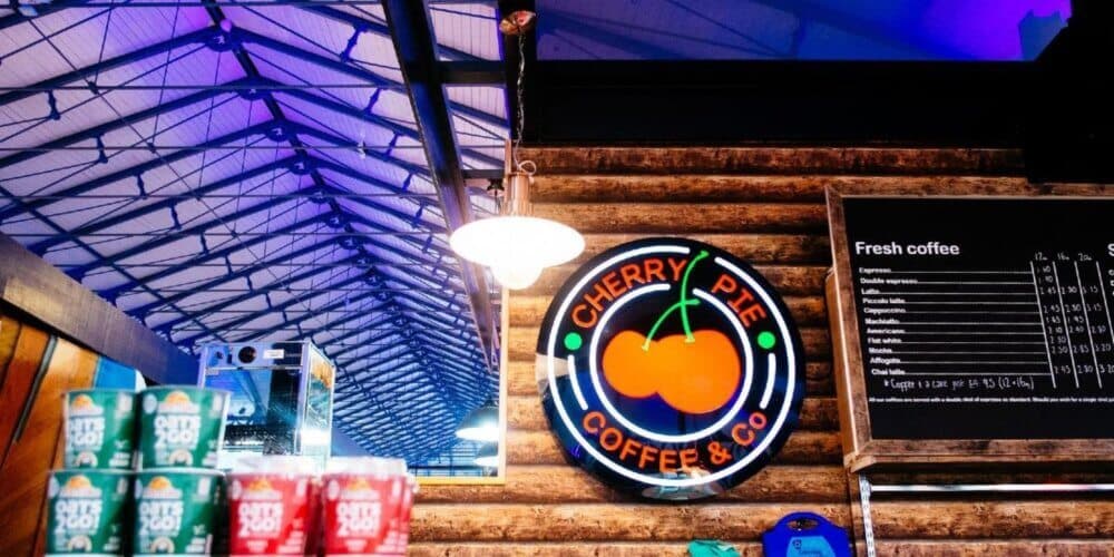 Interior of a coffee shop with a sign reading "Cherry Pie Coffee & Co" and a blackboard menu listing various coffee options. - Home Instead