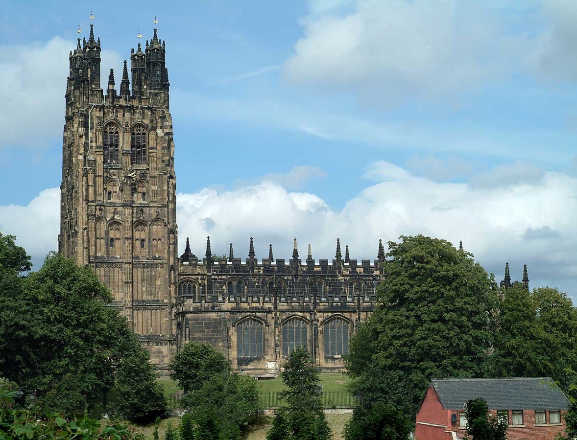 Large gothic-style cathedral with tall towers, surrounded by trees under a blue sky with clouds. - Home Instead