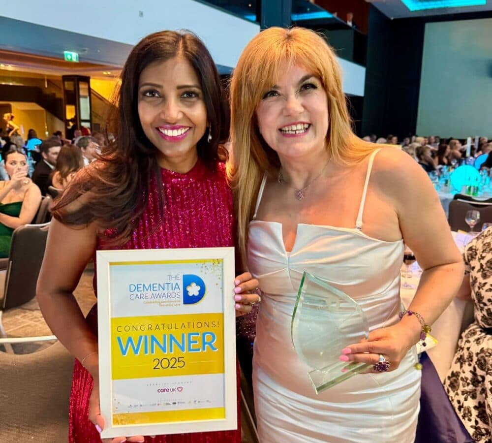 Two women inside the hotel both happy and smiling while holding an award