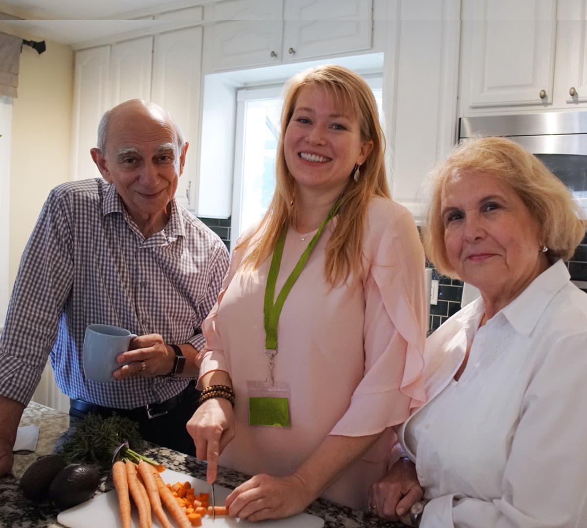 Three people in the kitchen preparing a meal and chopping vegetables inside the kitchen - Home Instead
