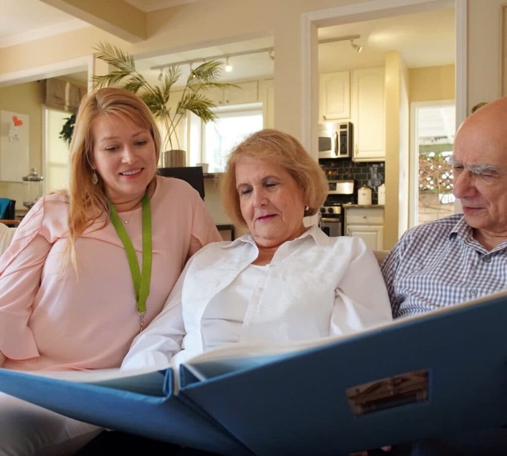 Looking at a photo album together while sitting on a couch inisde the house