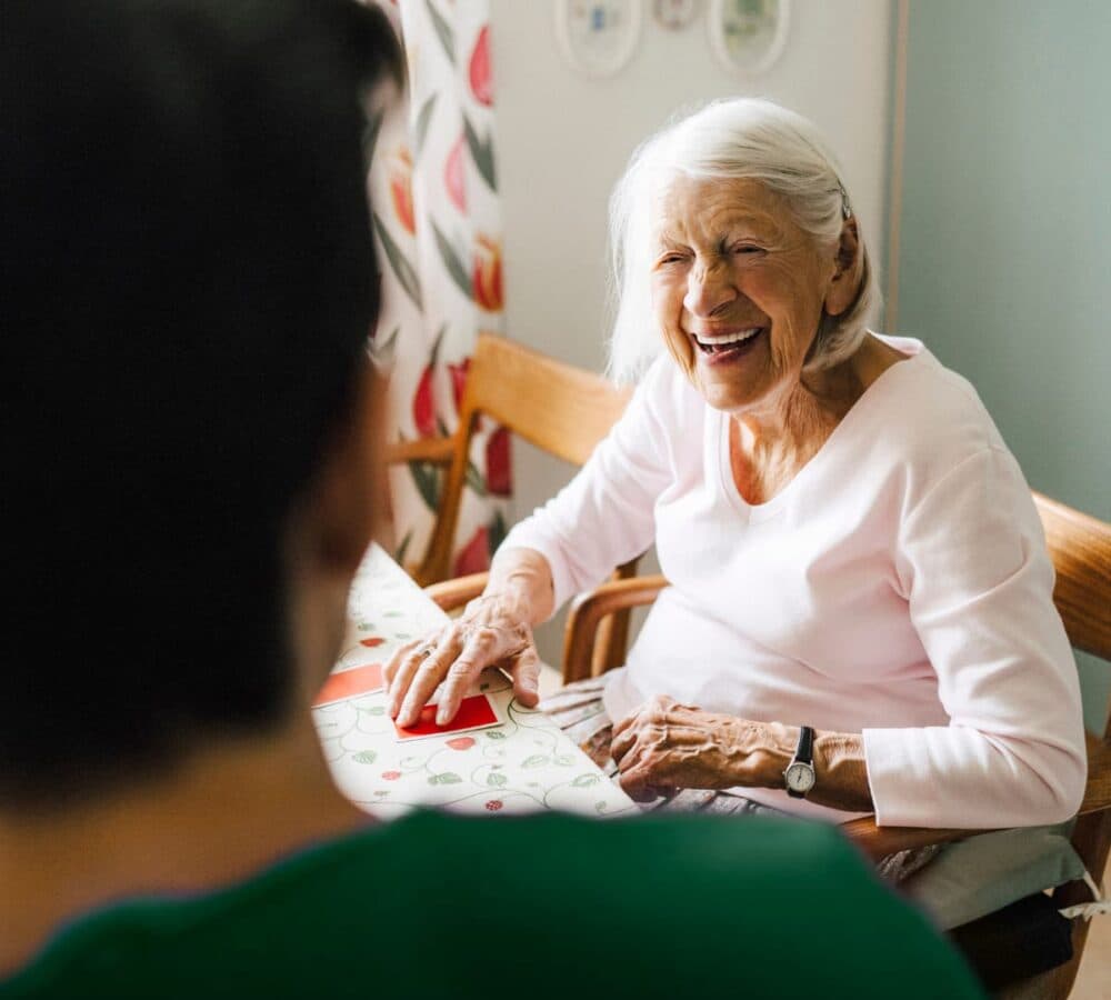 An older female adult with grey hair and sitting on a chair happy and smiling