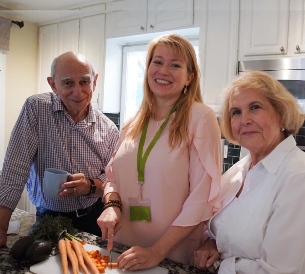 Three people preparing meal happy ad smiling inside the kitchen