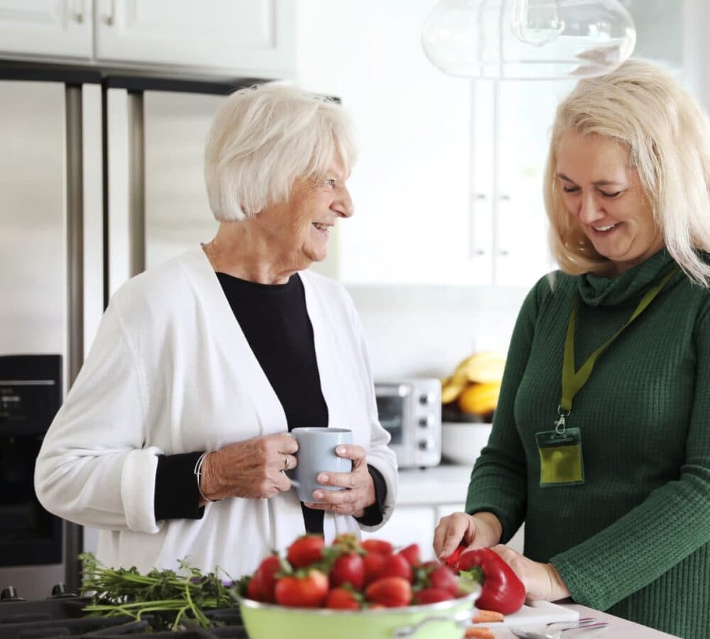Two people cooking vegetables in the kitchen both happy and smiling
